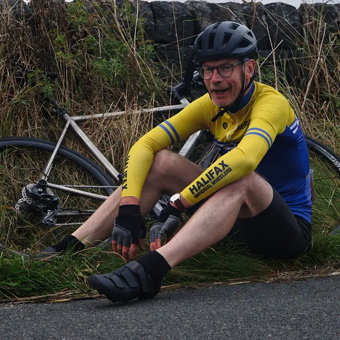 Exhausted rider sitting beside his bike after a hill climb