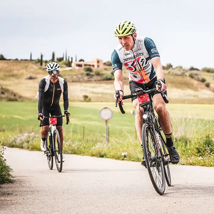 Two club riders climbing a sunlit Mallorcan road