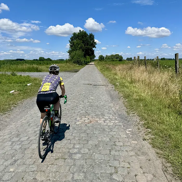 Club rider tackling a cobbled sector in the sunshine