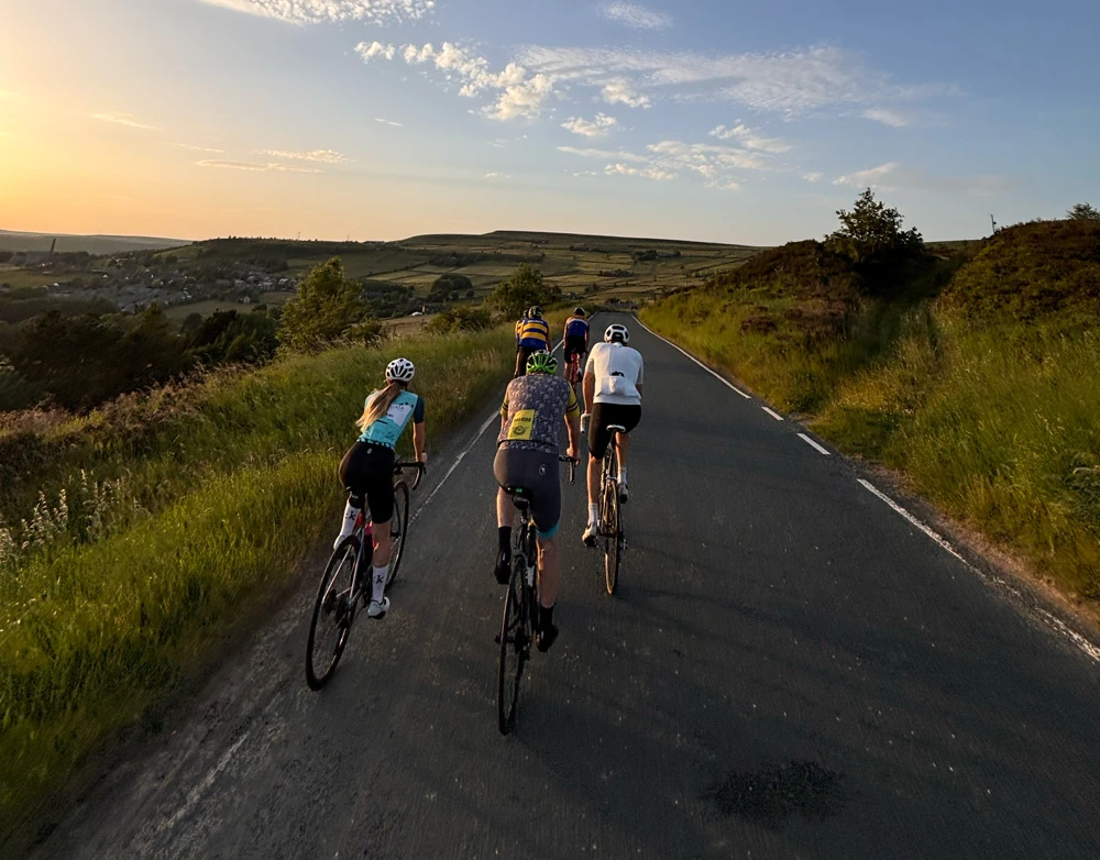 Club riders heading up a moor road at sunset